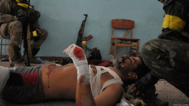 Бійці в коридорі іловайської школи перев'язали і допомагають своєму пораненому командиру | Фото: Маркіян Лисейко