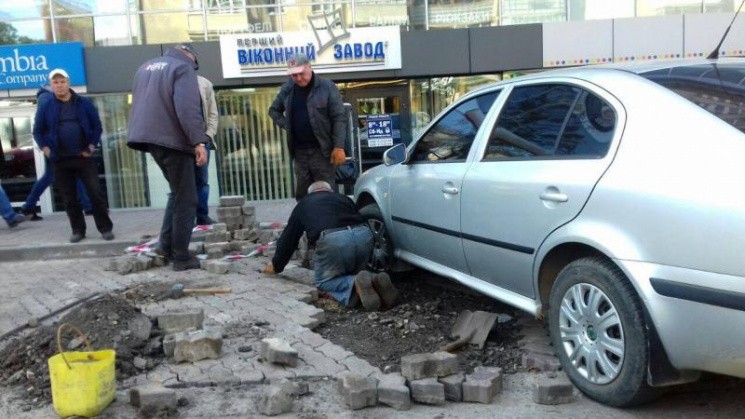 Майстрам доводиться вимощувати вулицю бруківкою під припаркованим автомобілем