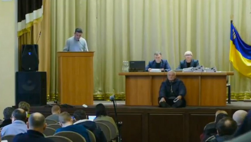 Нестор Литвин трохи посидів на сцені перед столом, за яким сидить міський голова та секретар міської ради. | Фото: Скрін