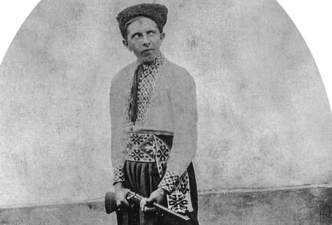 На фото Степан Бандера в козацькому строї — шапці кучмі, чоботах, шароварах, сорочці та з гвинтівкою в руках