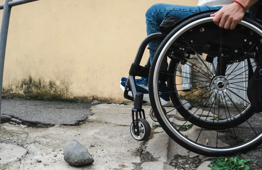 Ілюстроване фото. Людині похилого віку на кріслі колісному важко пересуватися до свого помешкання