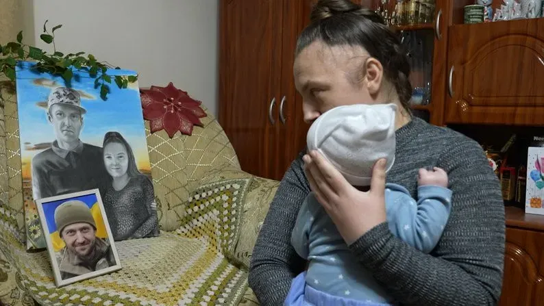 Оксана Гавришко із сином Мирославом біля портрета чоловіка Ярослава Гавришка, який загинув на війні. Суспільне Івано-Франківськ